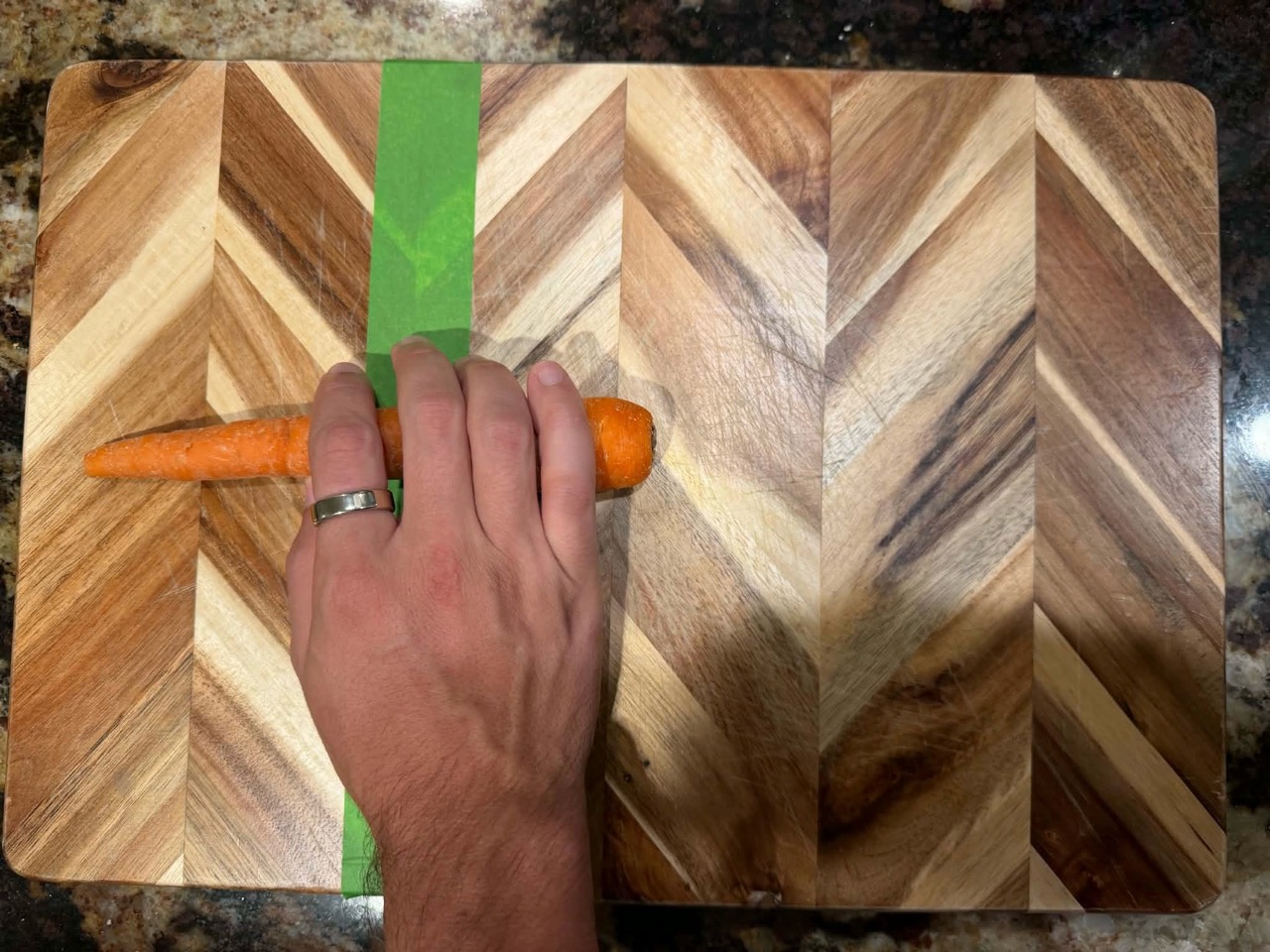Hand covering the carrot where it crosses the green tape